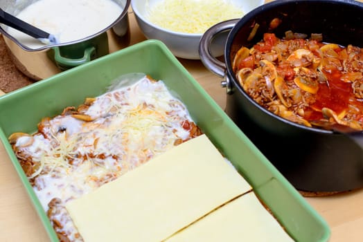 preparation of lasagna in a green dish