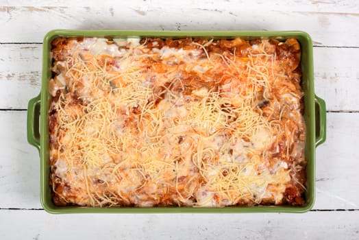 preparation of lasagna in a green dish on white table