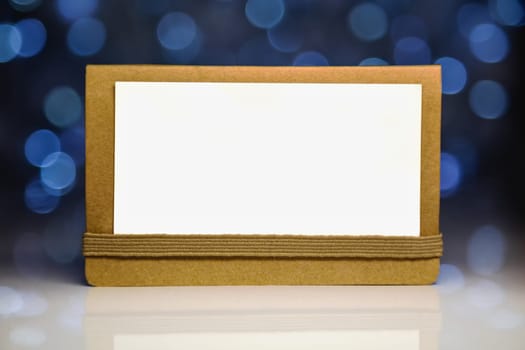 Greeting white blank card on craft paper with reflection on Christmas lights background