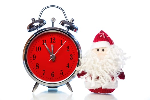 Santa Claus or Father Frost and vintage alarm clock with red dial on white background with reflection. Showing time five minutes before twelve midnight