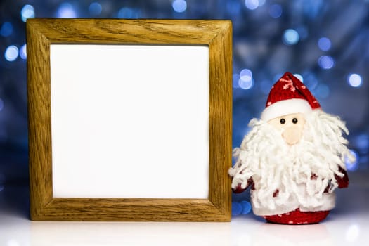 Santa Claus or Father Frost and greeting blank wooden frame with white backdrop on Christmas lights background