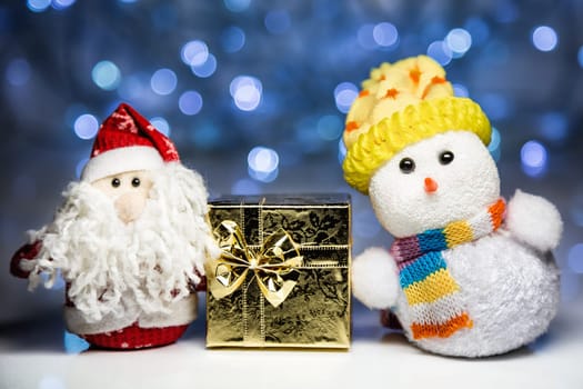 Santa Claus or Father Frost and Snowman with gold gift box on christmas lights background