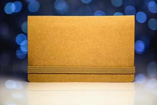 Greeting brown blank card from craft paper with reflection on Christmas lights background