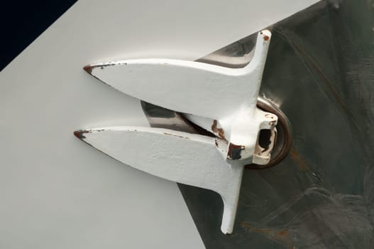 Up close view of an anchor of a yacht, retracted against the hull of the vessel.