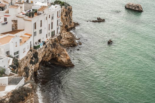 Old houses and apartments situated precariously on the edge of the rocks right next to the sea.