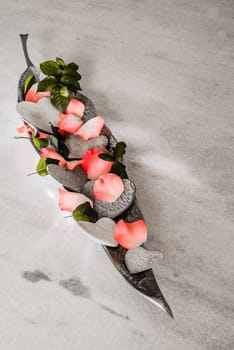 porcelain hearts and rose pebbles in a silver bowl as decoration and an offering.