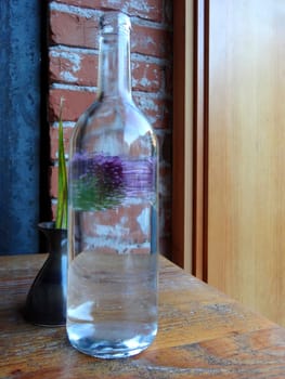 Still life of a bottle and a flower in a vase
