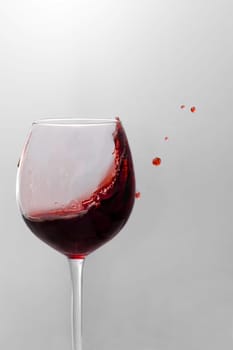 Red wine is splashing out of a wine glass