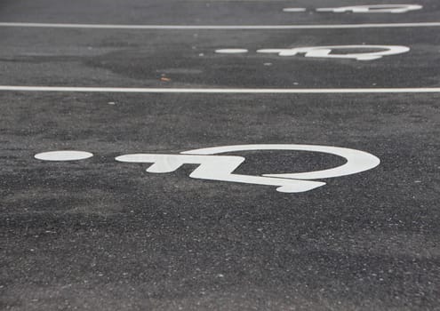 Line of White Handicap Disabled Sign on Black Asphalt