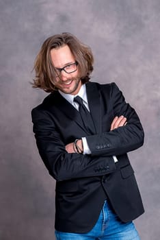 portrait of a young friendly business man in black suit in front of gray background