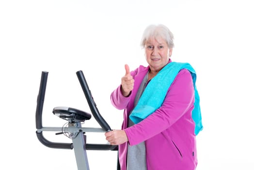 gray-haired female senior with thumb up train with fitness machine