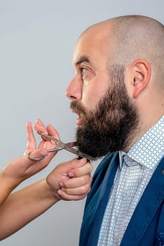 young man is not so happy with beard- cutting