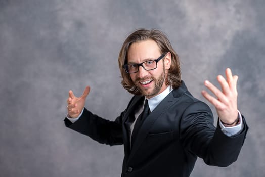 young friendly business man in black suit in front of gray background