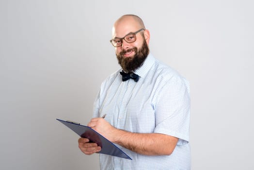 young bearded man with clipboard in front of gray background