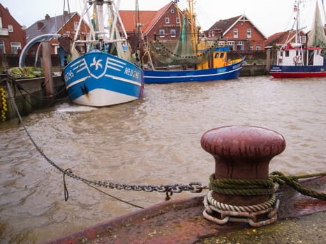 Neuharlingersiel,Germany - December 25,2014: Fishing boat moored in the port of Neuharlingersiel on a bollard in the foreground