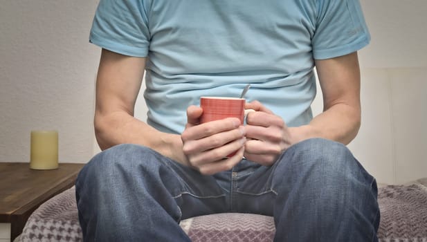 Young man sitting on a couch with a pot of coffee