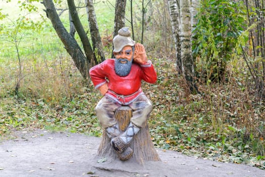 Orel, Russia - October 18, 2015: Sculpture of an old man sitting on a stump in a forest in the national park "Orlovskoye Polesie"""