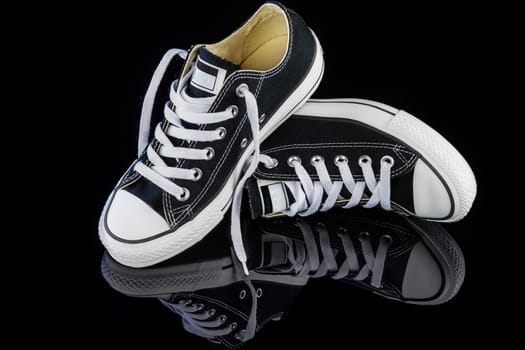 Black sneakers on black glossy background.