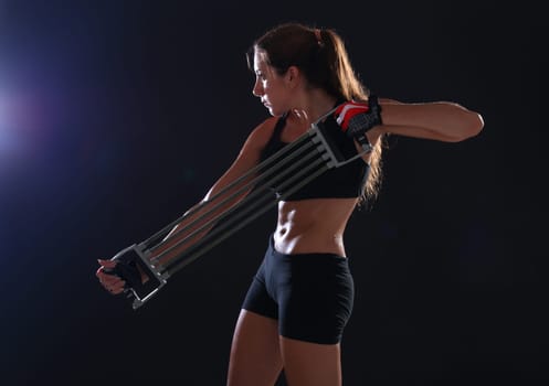 Fitness. Young woman doing exerciseover black background
