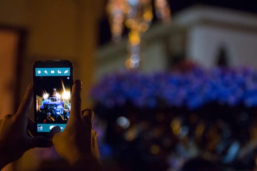 Tourist taking pictures with mobile phone to holy week float, Spain