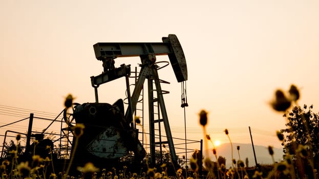 pumpjack at an oil drilling site and sunset