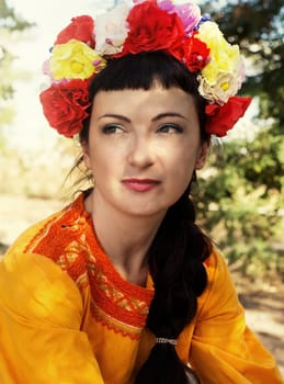 charming woman in wreath of roses on her head on the background of nature
