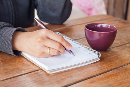 Woman hand with pen writing on notebook, stock photo