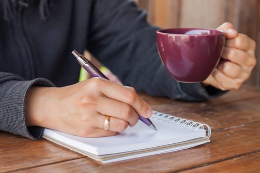 Woman hand with pen writing on notebook, stock photo