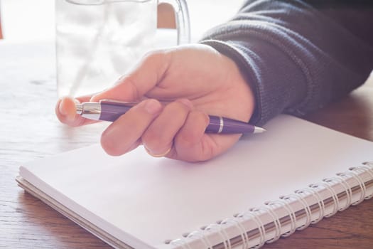 Woman hand with pen writing on notebook with vintage style