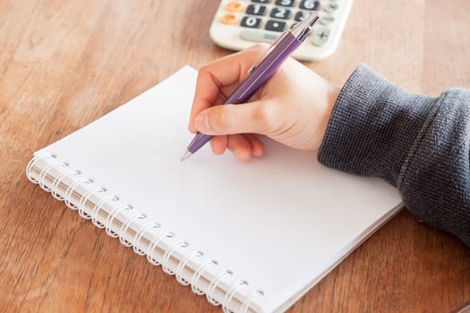 Woman hand with pen writing on notebook, stock photo