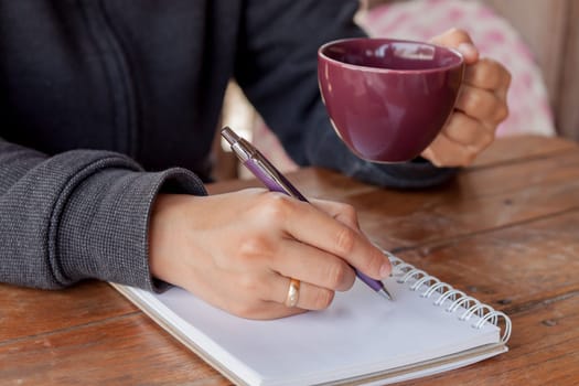 Woman hand with pen writing on notebook, stock photo