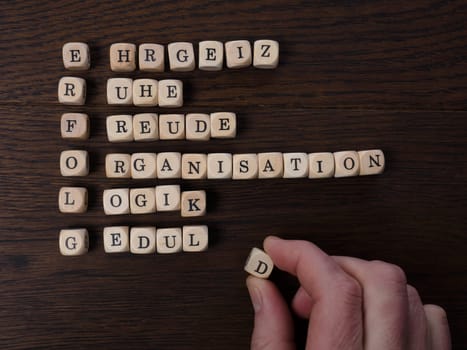 Businessman writing with wooden dices the German word Erfolg. Success concept with cross words