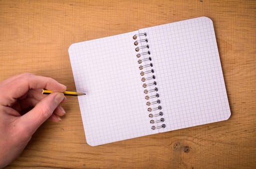 Male hand with a notebook on a wooden table
