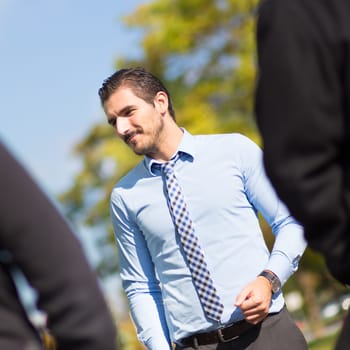 Attractive young businessman with a friendly smile having informal out of office meeting on a suny day.