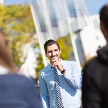 Attractive young businessman with a friendly smile having informal out of office meeting on a suny day.