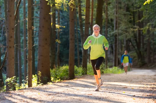 Pretty young girl runner in the forest.  Running woman. Female Runner Jogging during Outdoor Workout in a Nature. Beautiful fit Girl. Fitness model outdoors. Weight Loss. Healthy lifestyle.