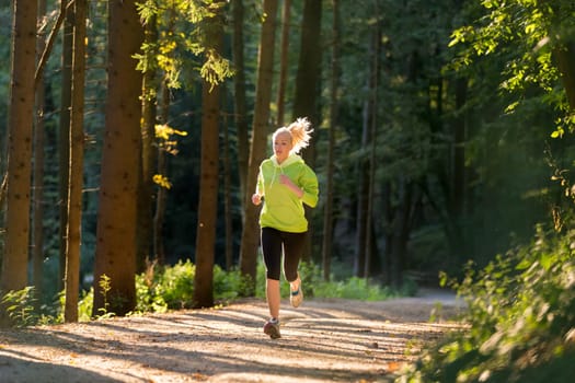Pretty young girl runner in the forest.  Running woman. Female Runner Jogging during Outdoor Workout in a Nature. Beautiful fit Girl. Fitness model outdoors. Weight Loss. Healthy lifestyle.