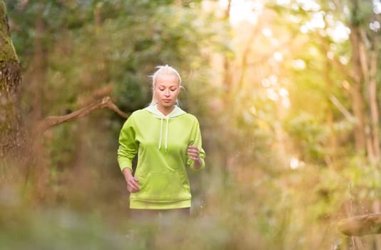Pretty young girl runner in the forest.  Running woman. Female Runner Jogging during Outdoor Workout in a Nature. Beautiful fit Girl. Fitness model outdoors. Weight Loss. Healthy lifestyle.