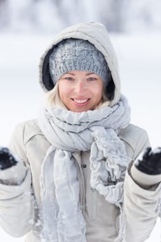 Cute casual young woman playing with snow in winter time.