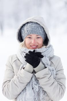 Girl wearing gloves, beeing cold outdoors in winter. Beautiful winter portrait of young woman in the winter snowy scenery.