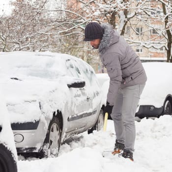 Man shoveling her parking lot after a winter snowstorm.