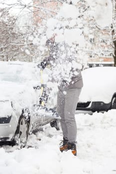 Man shoveling her parking lot after a winter snowstorm.