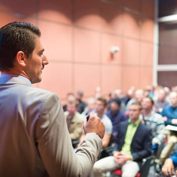 Speaker at Business Conference with Public Presentations. Audience at the conference hall. Business and Entrepreneurship concept. Background blur. Shallow depth of field.