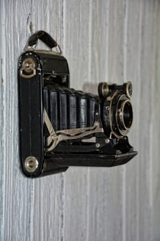 old camera hangs on old white wooden wall