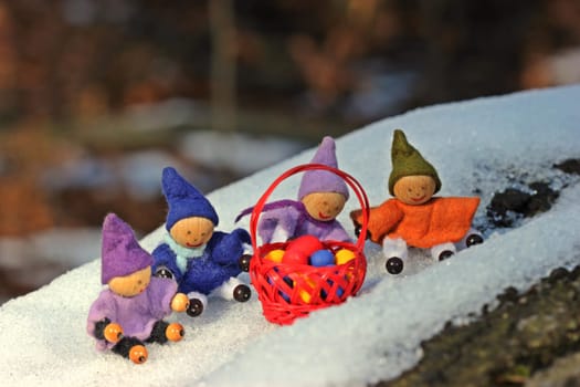 Four little gnomes with Easter eggs sitting in the snow