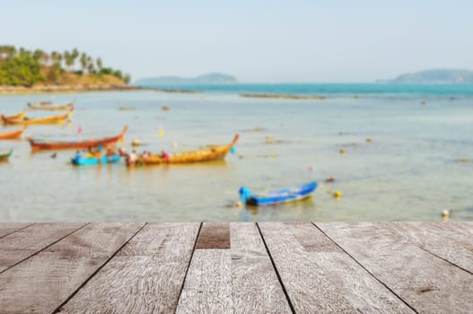 Wood table top on blurred blue sea and fishing boat with some people - Can be used for display or montage your products