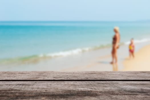 Wood table top on blurred blue sea and white sand beach with some people - Can be used for display or montage your products