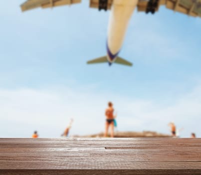 Wood table top on blurred blue sea and white sand beach with some people and plane, Can be used for display or montage your products
