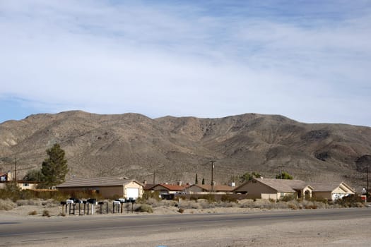 Detached houses on a street in Barstow with a mountain range in the background.