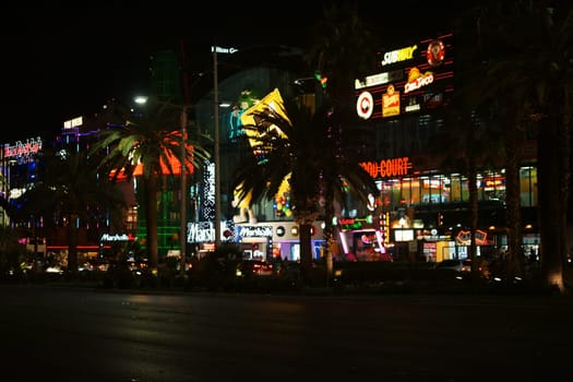 Las Vegas,United States - December 23,2015: Traffic on Las Vegas Boulevard with a collection of shrillly lit shops and shops behind a row of palm trees on the night of December 23,2015 in Las Vegas.